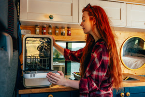 Person cleaning a dishwasher in a compact kitchen.