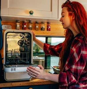 Person opening a portable dishwasher in a RV.
