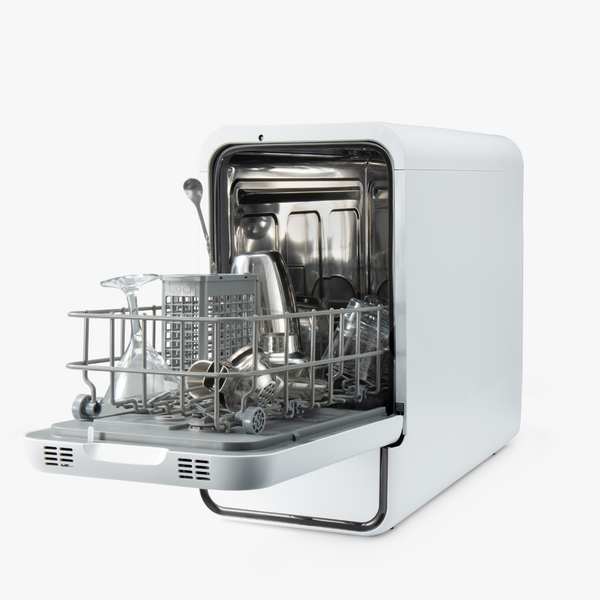 Small white dishwasher with open door displaying clean dishes on a white background