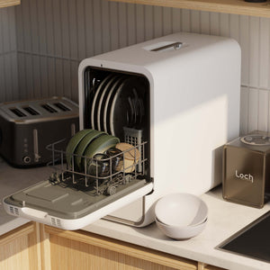 Portable dishwashing machine on a kitchen counter with dishes inside, next to a toaster and a container labeled 'Loch'.